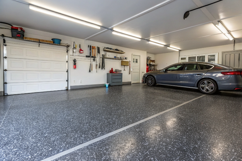 Refinished residential garage floor in Ipswich showing charcoal grey epoxy coating with decorative flakes and modern organized storage